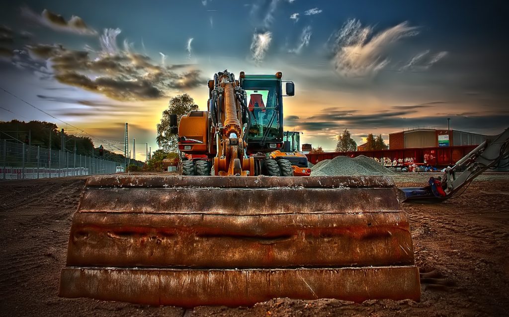 Construction excavator on job site illustrating work in process schedule management.